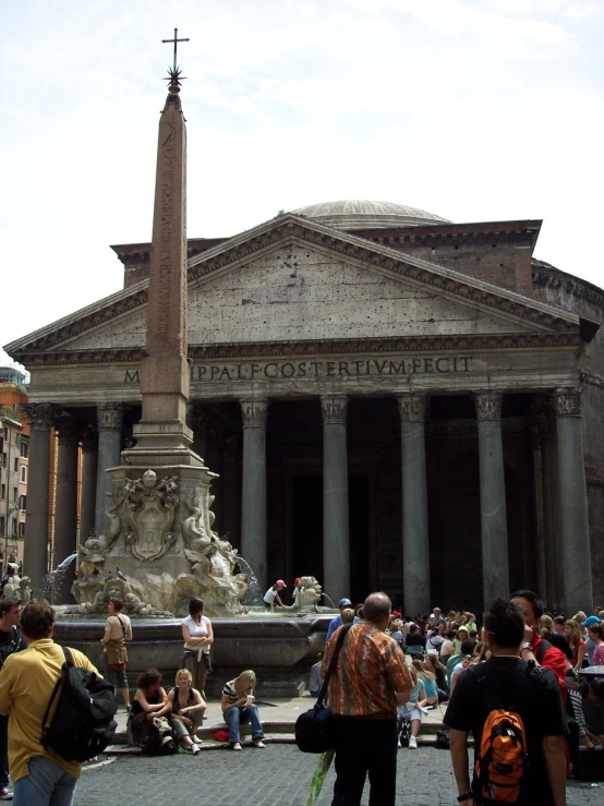 a crowd of people standing around a large building with a tall column