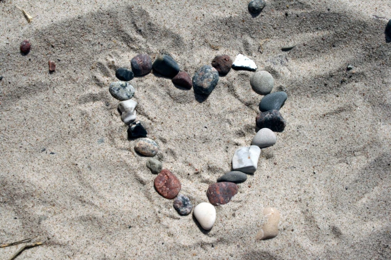 a heart shaped arrangement of different rocks on the beach