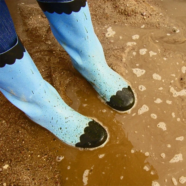 a view of one legs in sandals and mud