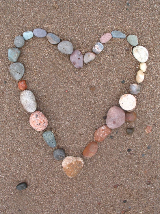 a heart shaped made out of rocks in the sand