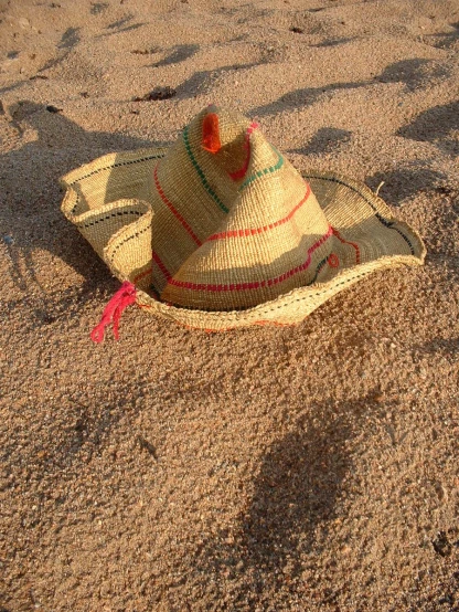a straw hat that is sitting in the sand