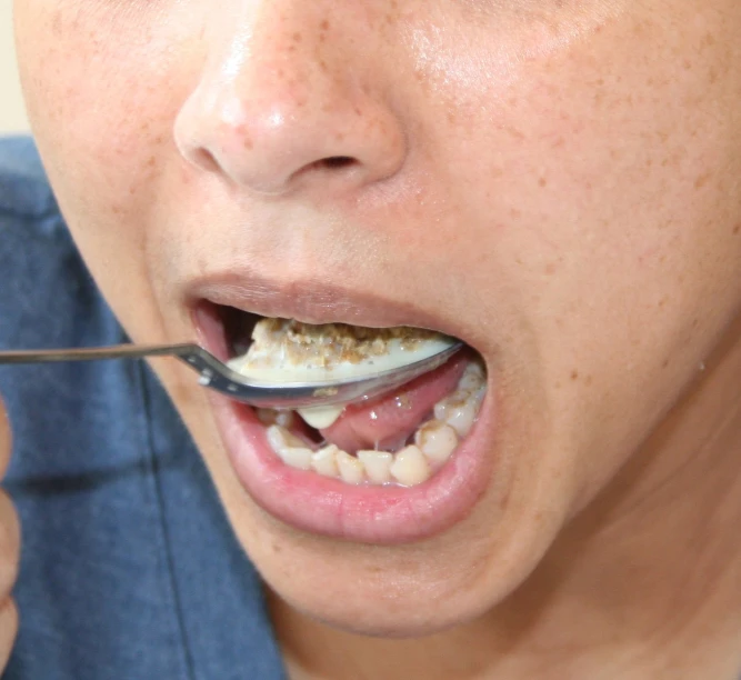 a person brushing their teeth with a spoon