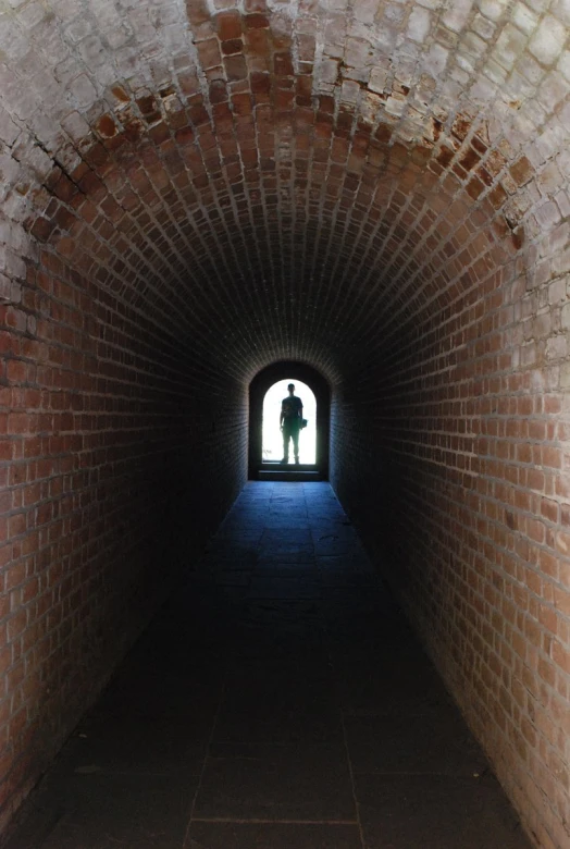 a person is standing in an entrance of a brick tunnel