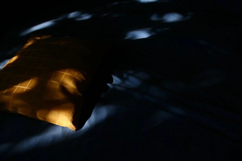 shadow over a yellow pillow on a black surface