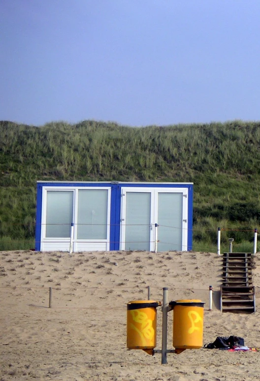 a beach with many trash cans and a hill behind it