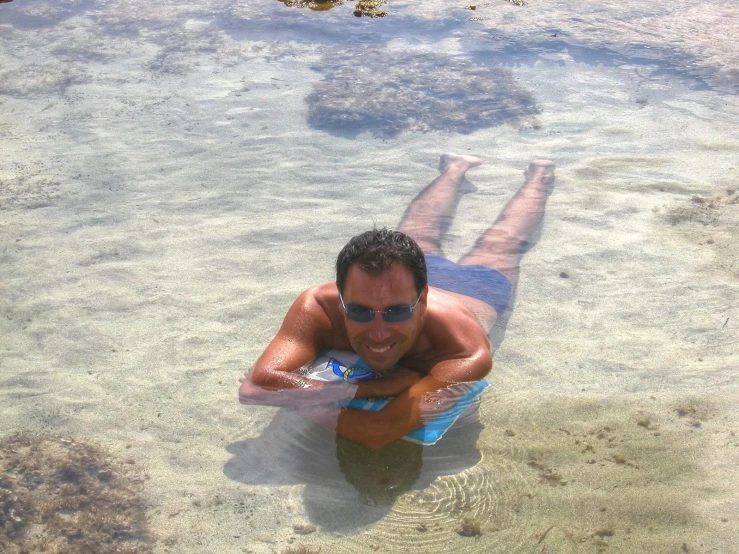 a young man laying on top of a blue surfboard in the water