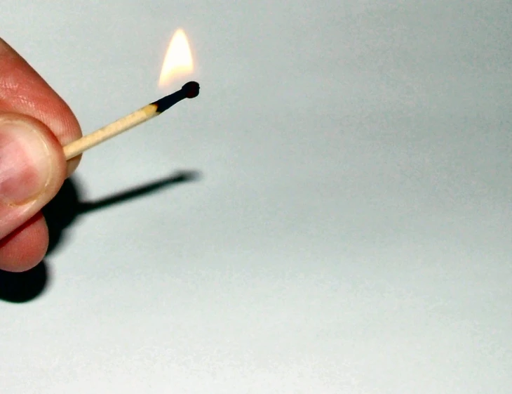a match lit with matchestick in hand with only one light