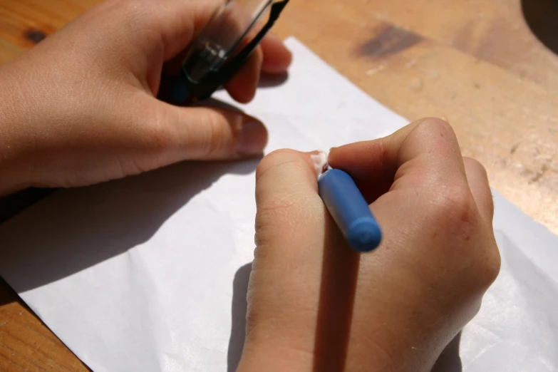 a person writing with a blue pen on a piece of paper