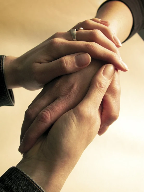 two people holding their hands together with a beige background