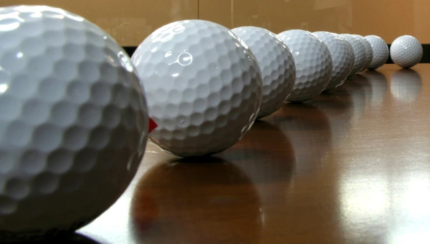 five golf balls lined up on a table in a row
