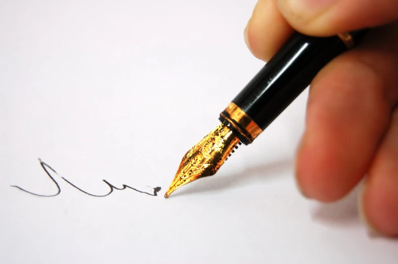 a hand is writing on a white paper with a black pen