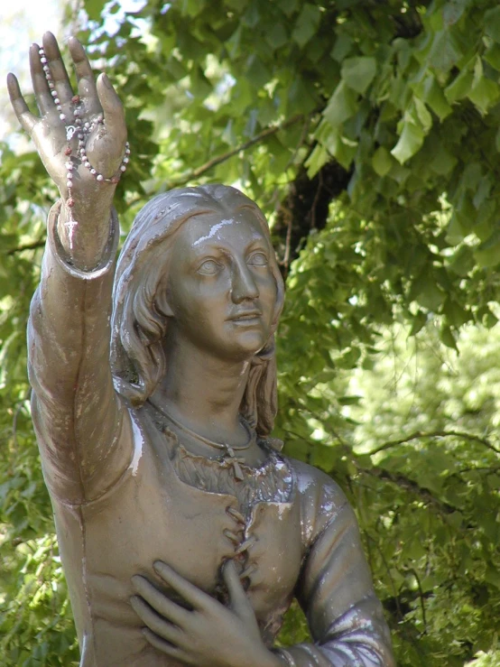 a silver statue in front of some trees