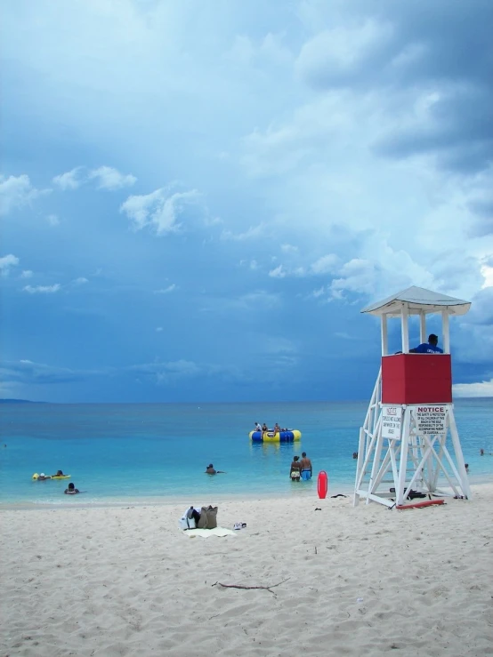 a lifeguard tower on a beach with people standing around