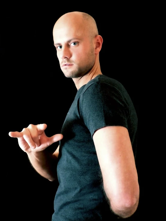 a man with a bald head and black shirt making a gesture