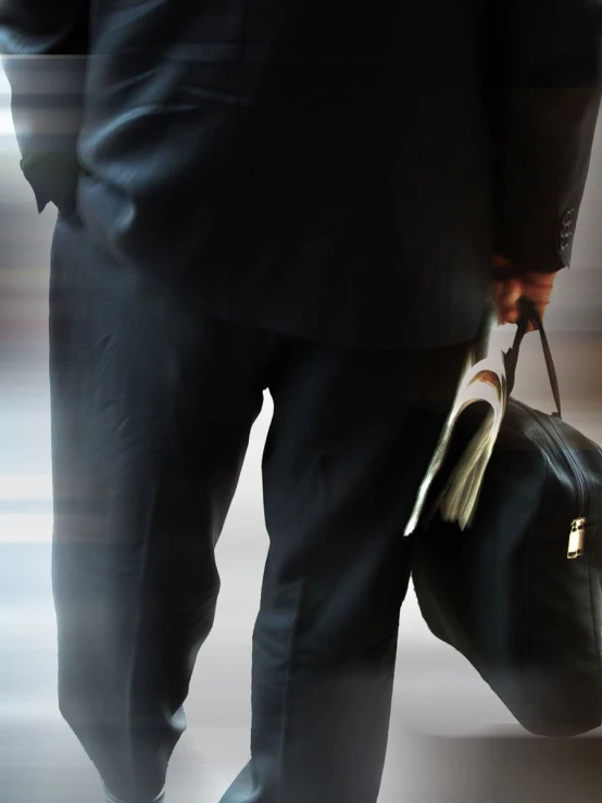 a person with black suit carrying a brown briefcase