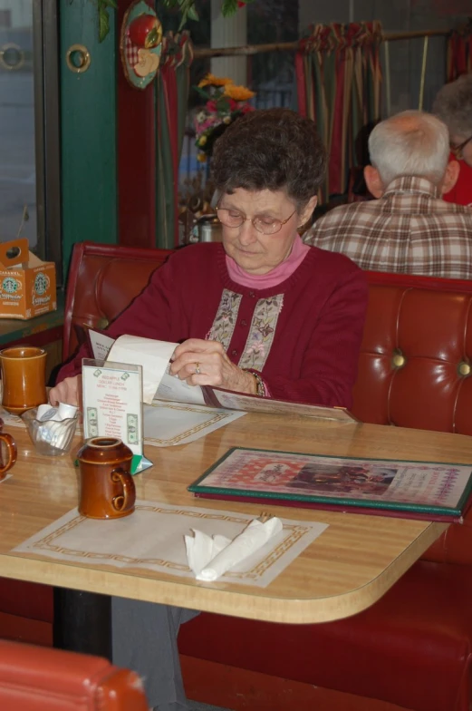 the woman sits at the table and signs the paper