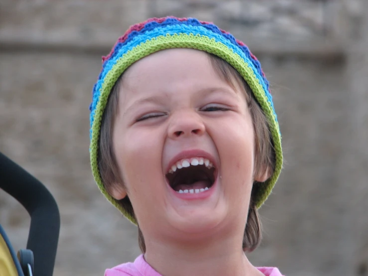 the little girl is wearing a hat laughing