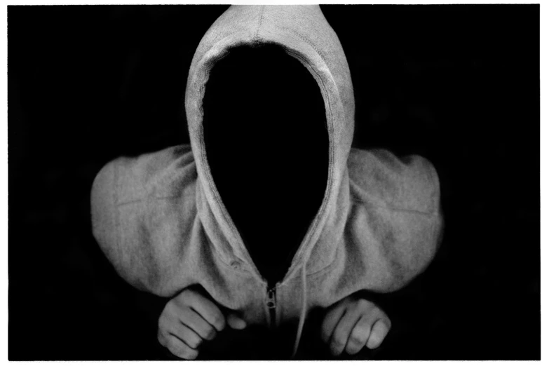 black and white pograph of hand in front of hooded jacket