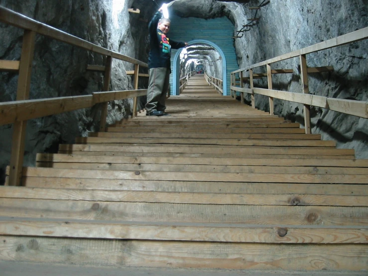 a man in black jacket standing on stairs next to rock