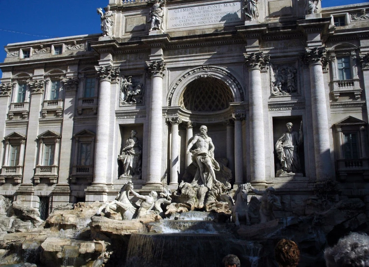 an old building with a fountain surrounded by statues and greenery