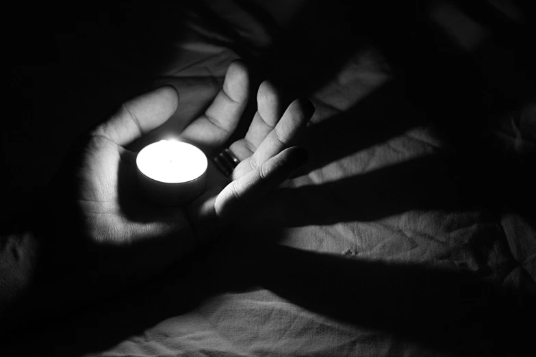 a dark room with a persons hands holding an illuminated candle