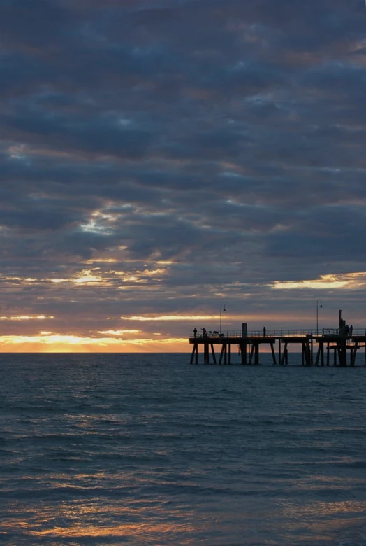 a long wooden pier with water below it and sky