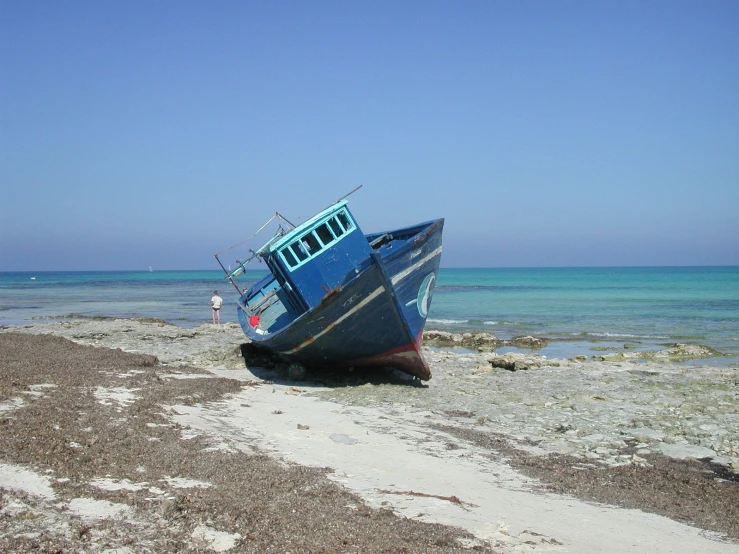 a boat on the sand with ocean in background