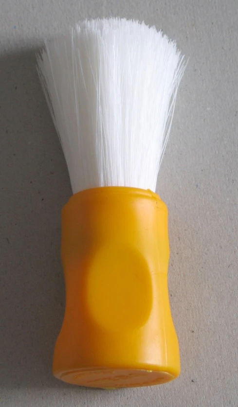 a small yellow shaving brush holder attached to the wall