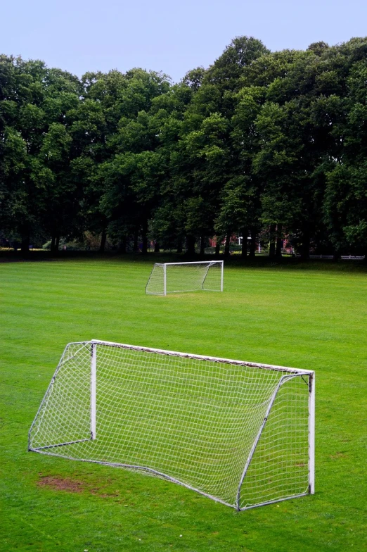 three different white soccer goal posts in the middle of a grassy field