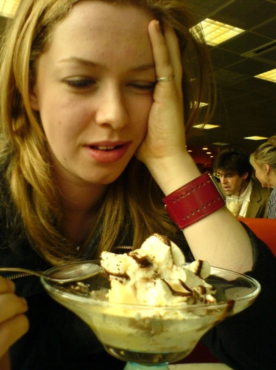 woman sitting at table with large dessert item in hand