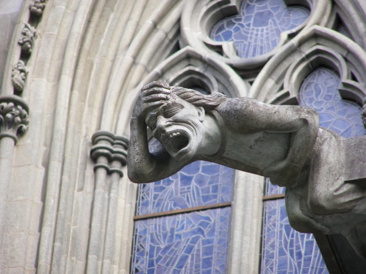 a statue is sitting near a window next to an old cathedral