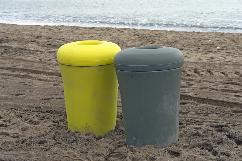 two trash cans in the sand at the beach