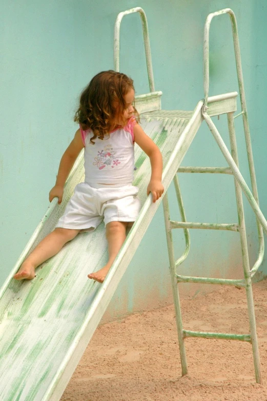 a little girl on a slide in the sand