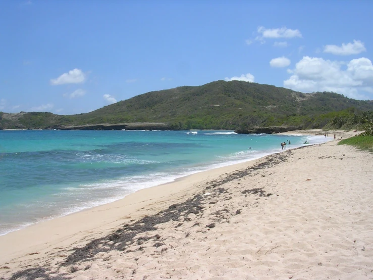 a small sandy beach with blue water and hills in the background