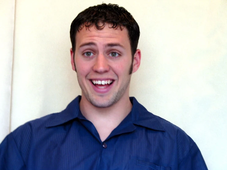 a man smiles broadly as he stands in front of the camera