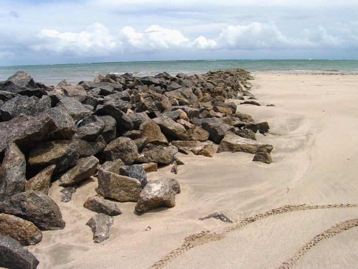 a rock wall sitting on top of a beach next to the ocean