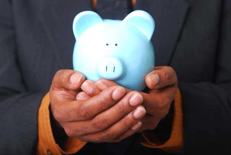 a man holding up a blue piggy bank