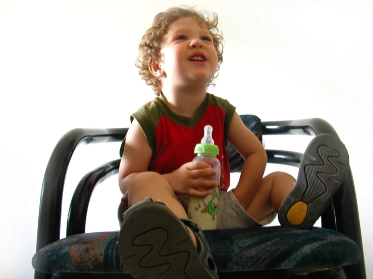 the small child is sitting down and holding a bottle