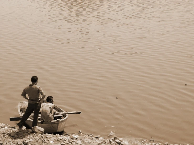 three people standing in a canoe near the edge of a body of water