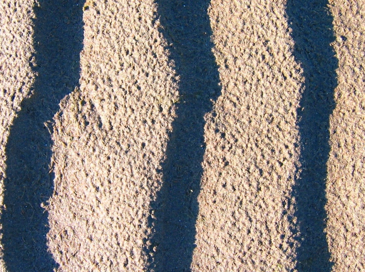 two shadows of people standing in sand against a blue sky