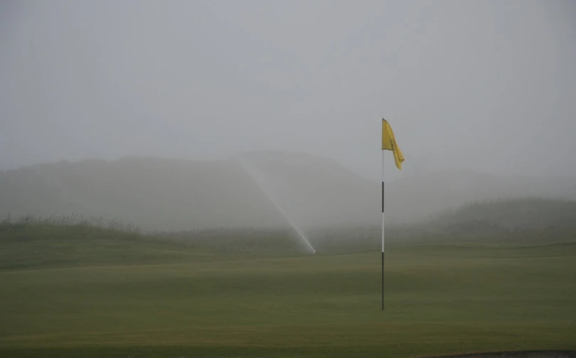 a foggy field with a golf flag