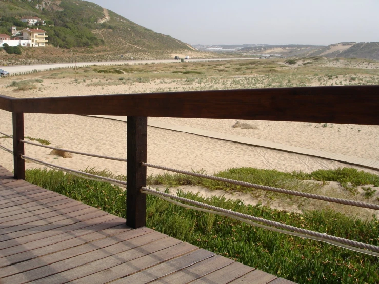 the railing over looking a sandy beach near homes