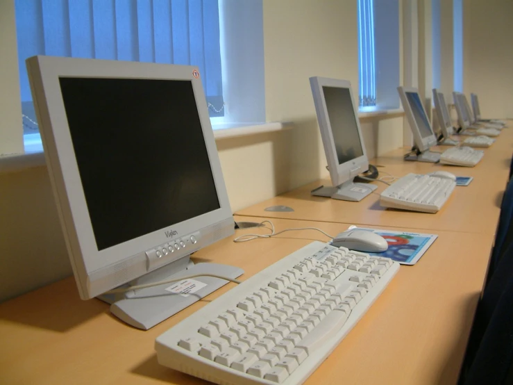 a row of computer monitors sitting on a desk
