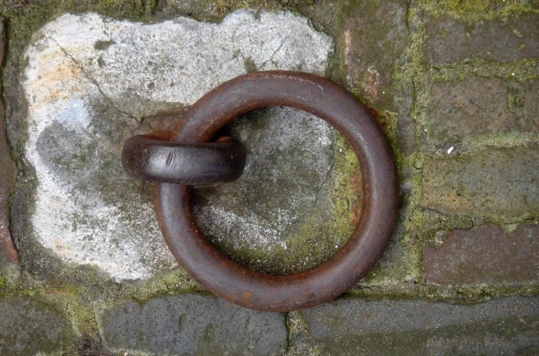 a rusty circular metal ring mounted to a brick wall