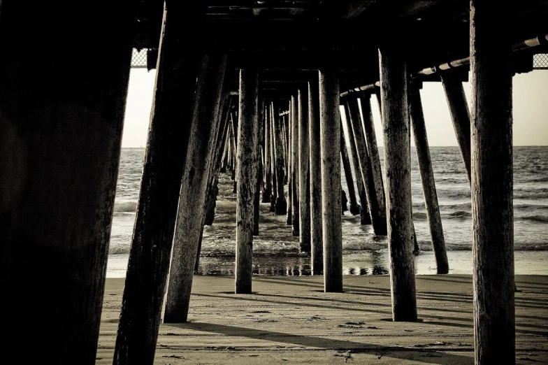 a view of the ocean from underneath a long pier