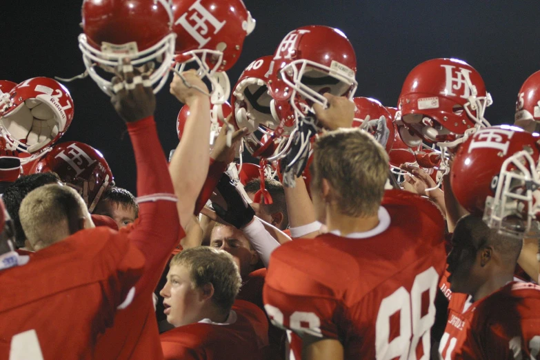 a group of boys in red jerseys holding helmets and cheering