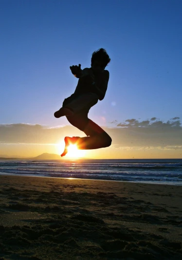 a silhouette of a person jumping up into the air at sunset