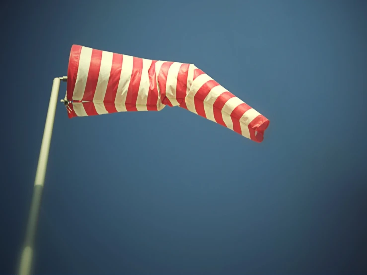 a striped flag waving on top of a pole