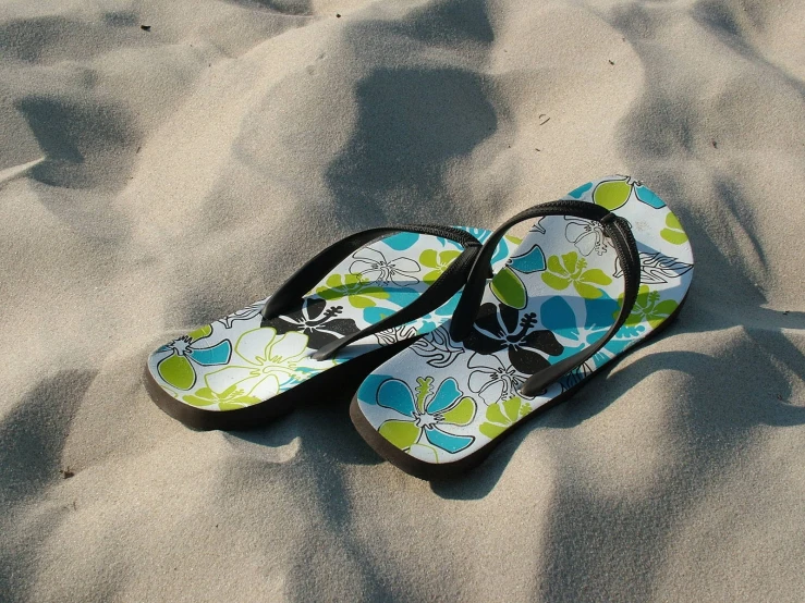 sandals laying on top of a sandy beach