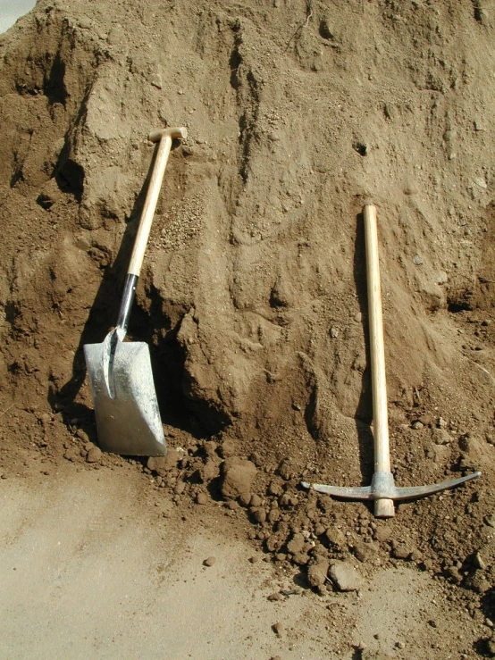 two shovels are sticking out from the dirt